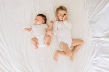 Beyaz bodysuits yatakta birlikte evde yatarken şirin küçük kardeşlerden havai görünümü
