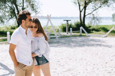 mutlu çift rahat kıyafetler ve sandy şehir sahilde duran güneş gözlüğü