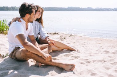sandy şehir beach Nehri yakınında oturan çift yan görünüm