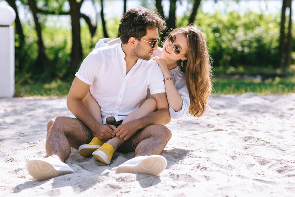 attractive girlfriend hugging boyfriend on sandy city beach