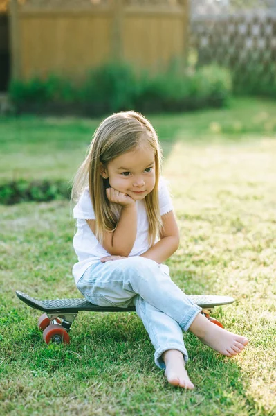 Entzückendes Kleines Kind Sitzt Auf Skateboard Auf Hof — kostenloses Stockfoto