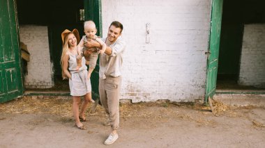 woman standing near husband with adorable little baby on hands at countryside  clipart