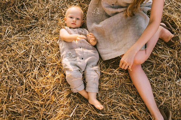 overhead view of mother and son in linen clothing resting on hay together