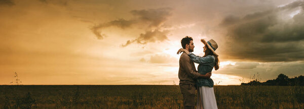 beautiful couple embracing on meadow at sunset