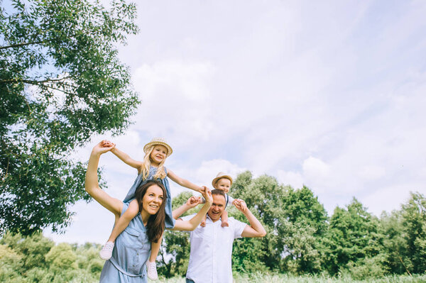 happy mother and father piggybacking son and daughter and spending time together