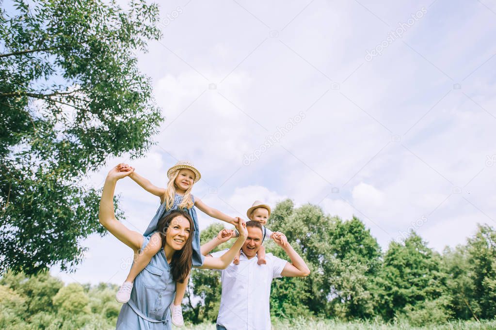 happy mother and father piggybacking son and daughter and spending time together