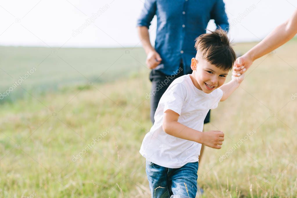 cropped image of parents and son running on field