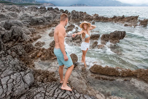 モンテネグロの岩のビーチで手を繋いでいる美しい幸せな若いカップル — ストック写真