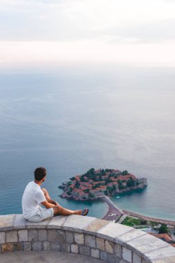 bakış açısı üzerinde oturan ve seyir, Sveti Stefan Adası otel resort Adriyatik Denizi'nde, Budva, Karadağ ile adam