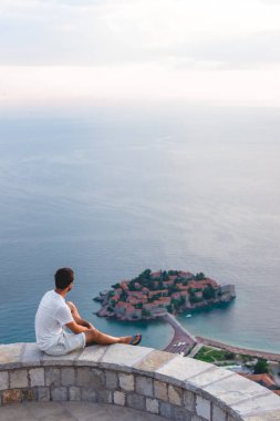 bakış açısı üzerinde oturan ve seyir, Sveti Stefan Adası otel resort Adriyatik Denizi'nde, Budva, Karadağ ile adam