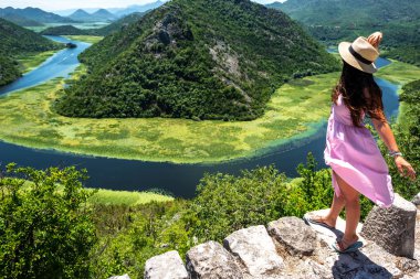 kadın pembe elbise ve şapka ayakta Karadağ'daki Crnojevica Nehri yakınında yüksek açılı görünüş