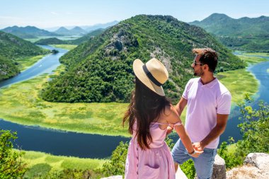 couple in pink clothes holding hands and looking at Crnojevica River in Montenegro clipart