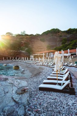 empty sun loungers on beach of adriatic sea with sunlight in Budva, Montenegro clipart