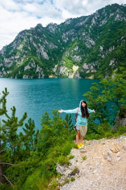 beautiful woman standing with open arms near Piva Lake (Pivsko Jezero) in Montenegro clipart