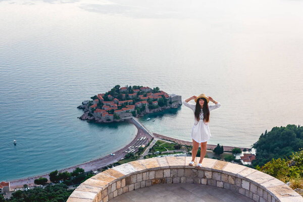 привлекательная женщина, стоящая на смотровой площадке возле острова святого Стивена в Адриатическом море, Будва, Черногория
