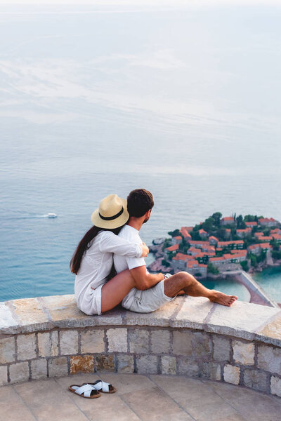 couple hugging and looking at island of Sveti Stefan in Adriatic sea, Budva, Montenegro 