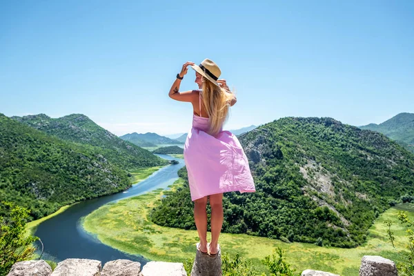 モンテネグロの Crnojevica 川に近い視点の石の上でピンクのドレスに立って女性の背面します — ストック写真