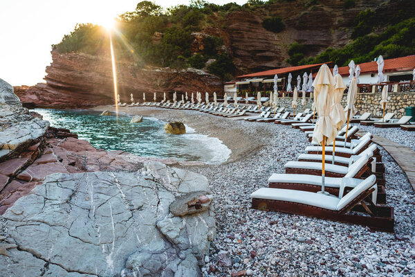 sun loungers on empty beach of adriatic sea with sunlight in Budva, Montenegro