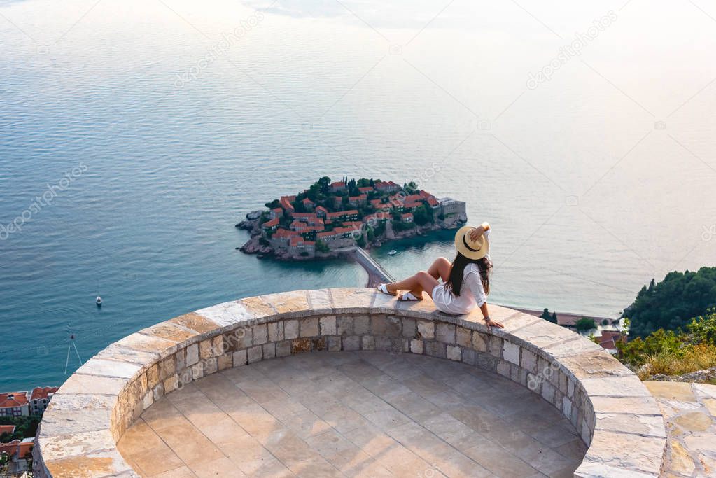 woman sitting on viewpoint near saint stephen island in Adriatic sea, Budva, Montenegro