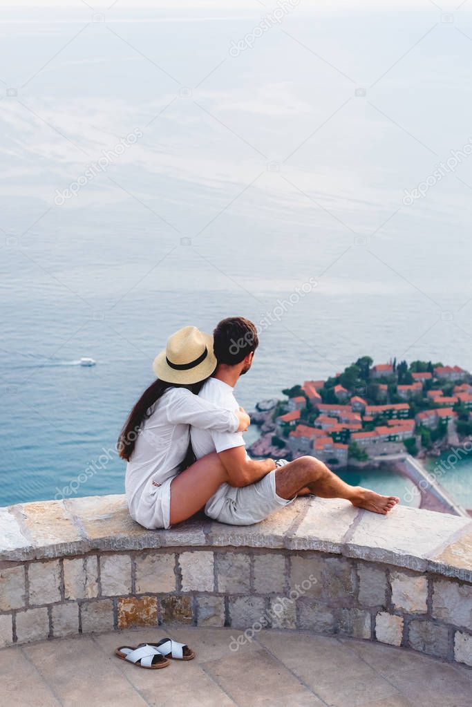 couple hugging and looking at island of Sveti Stefan in Adriatic sea, Budva, Montenegro 