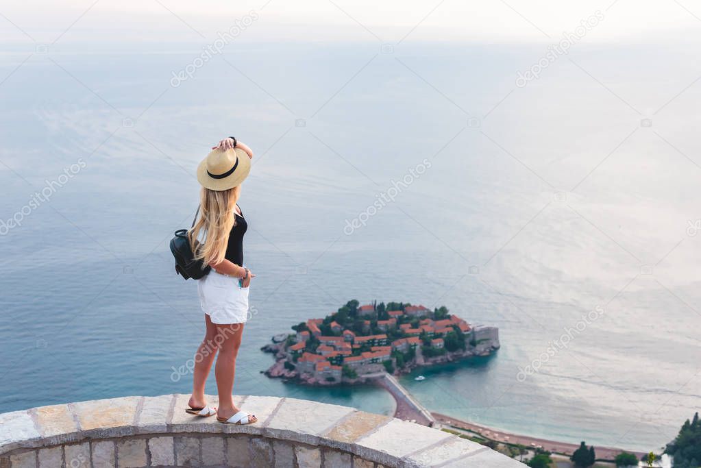woman standing and looking at saint stephen island in Adriatic sea, Budva, Montenegro 