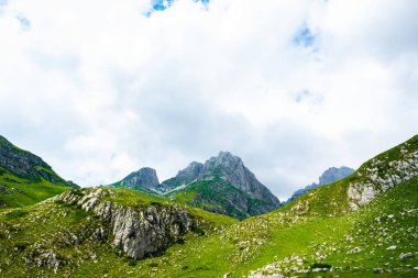 rocky mountains, green grass and cloudy sky in Durmitor massif, Montenegro clipart