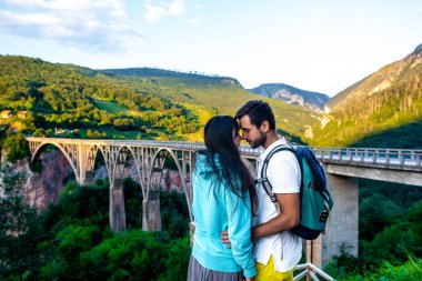 couple hugging and touching with foreheads near bridge in Montenegro clipart