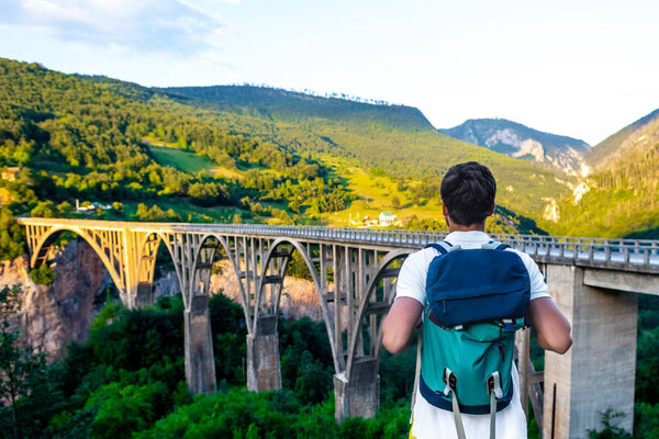 вид сзади туриста с рюкзаком, смотрящего на мост Тары в Черногории
