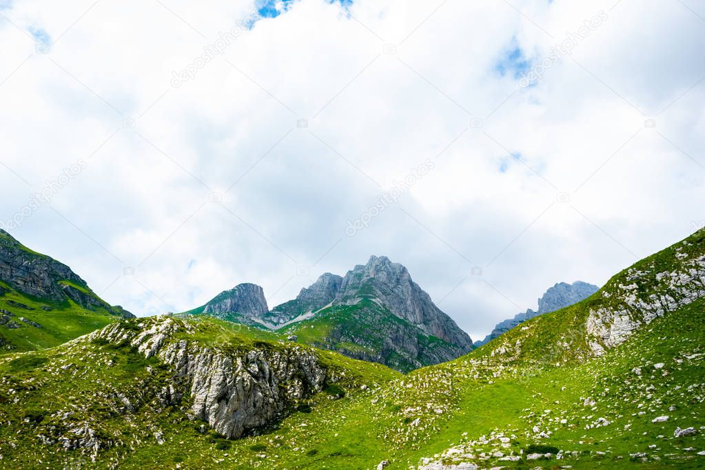 rocky mountains, green grass and cloudy sky in Durmitor massif, Montenegro