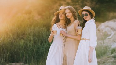 sarılma ve güneş ışığı ile kahve latte tutan hasır şapkalar şık kız