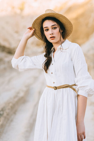 attractive stylish girl in straw hat posing in sandy canyon