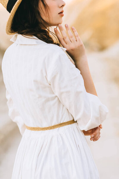 cropped view of girl in white dress posing in sandy canyon
