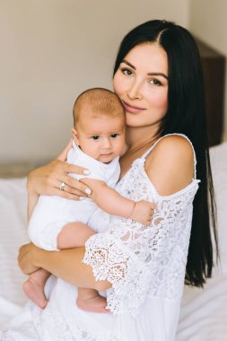 evde yatakta oturup onun küçük oğlu ile çekici genç anne
