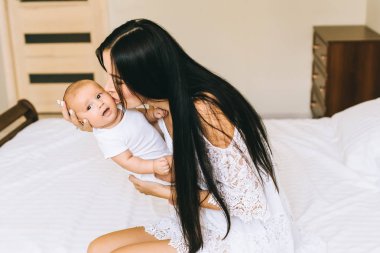 mutlu genç anne ve bebek ile evde yatakta otururken sarılma