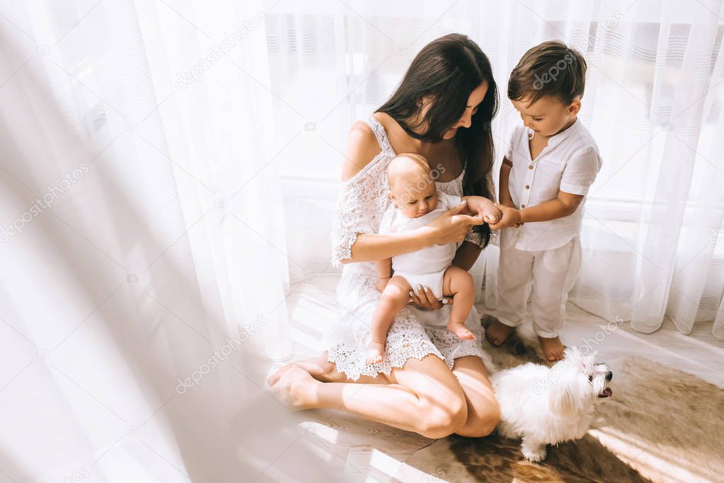 high angle view of beautiful happy mother sitting on floor with kids and bichon dog