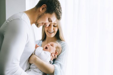 gülümseyen aile taşıyan küçük oğlu evde perdeler önünde