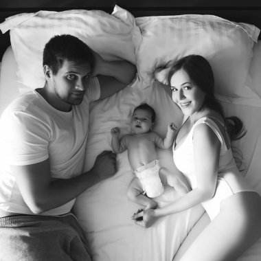 mutlu aile evde, yatakta çok güzel küçük bebek oğluyla siyah ve beyaz döşeme yüksek açılı görünüş