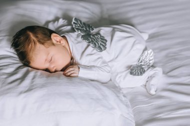 sevimli küçük oğlu evde yatakta uyuyan kanatlı kostüm