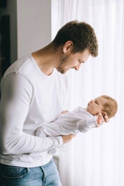 küçük oğlu evde perdeler önünde taşıyan neşeli baba