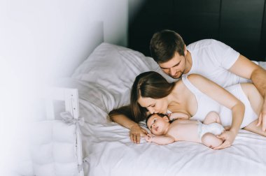 ailesinin evde yatakta çok güzel küçük bebek oğluyla döşeme seçici odak