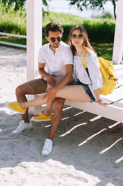 Гетеросексуальна пара сидить на дерев'яній лавці на піщаному міському пляжі — стокове фото
