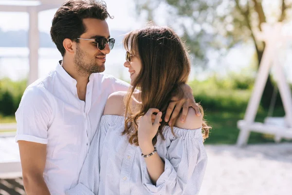 Porträt eines Paares mit Sonnenbrille, das sich am Stadtstrand anschaut — Stockfoto