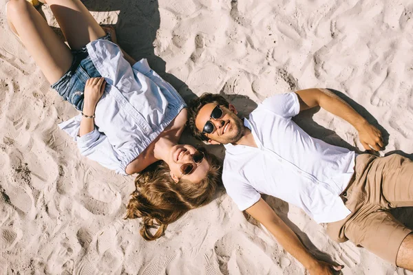 Vista elevada de casal sorridente deitado na praia da cidade arenosa — Fotografia de Stock