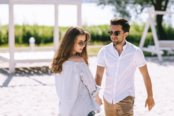 Coppia in occhiali da sole e abiti casual sulla spiaggia sabbiosa della città — Foto stock