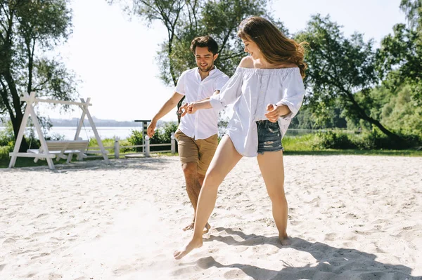 Feliz pareja divirtiéndose en la playa de arena ciudad - foto de stock