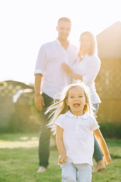 Избирательный фокус маленького ребенка, бегущего в то время как родители стоят позади на заднем дворе — стоковое фото