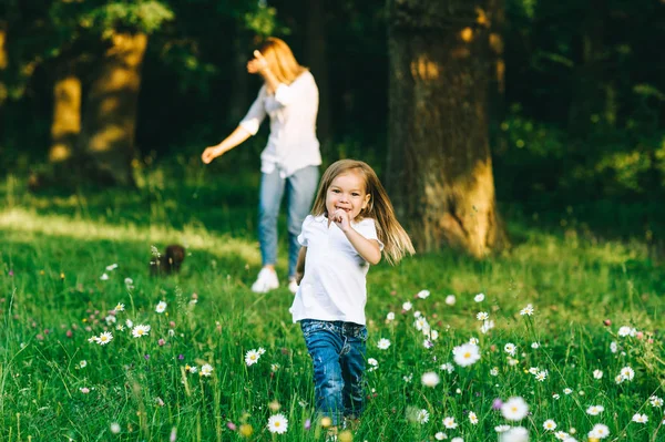 Messa a fuoco selettiva del bambino sorridente che corre con la madre in piedi dietro nella foresta — Foto stock