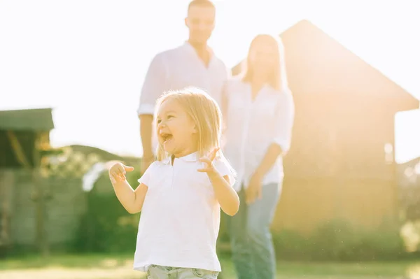 Foyer sélectif du petit enfant heureux avec des parents derrière sur la cour arrière — Photo de stock