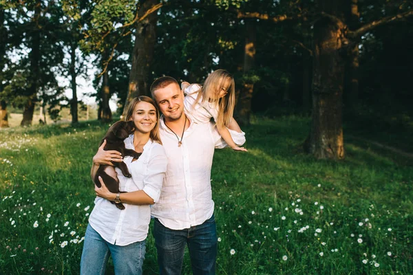 Retrato de padres sonrientes con hija y perrito labrador en bosque - foto de stock