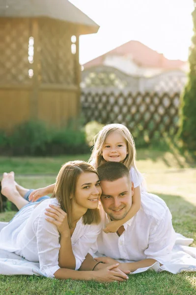 Famiglia con figlioletta poggiata su un panno a terra insieme sul cortile — Foto stock